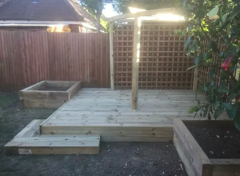 a wooden deck in a back yard with a trellis